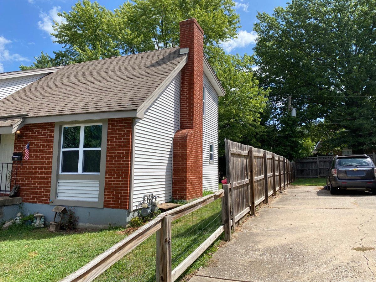 A house with a fence around it and trees in the background.