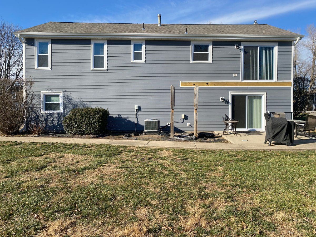 A house with a dog sitting in the yard.