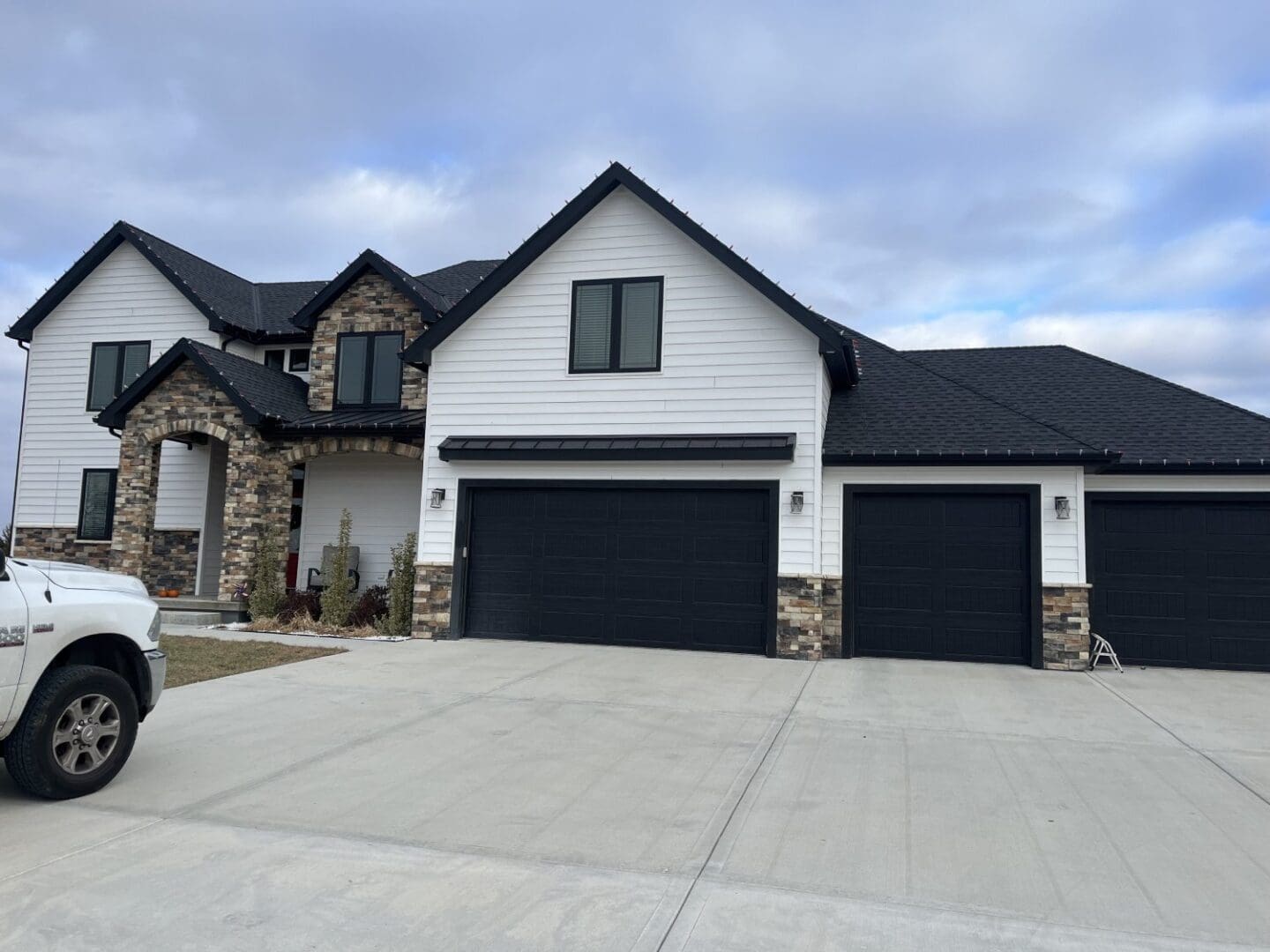 A large white house with two black garage doors.