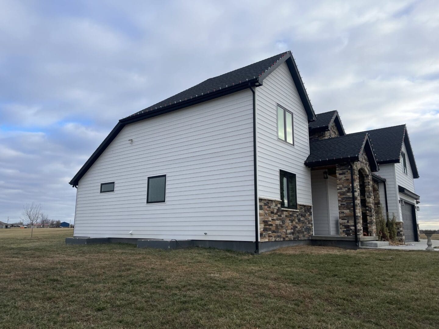 A white house with black roof and stone accents.