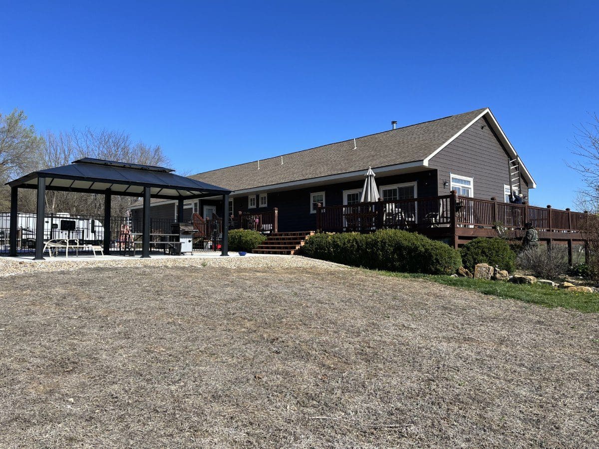 A large house with a covered patio and a grassy area.