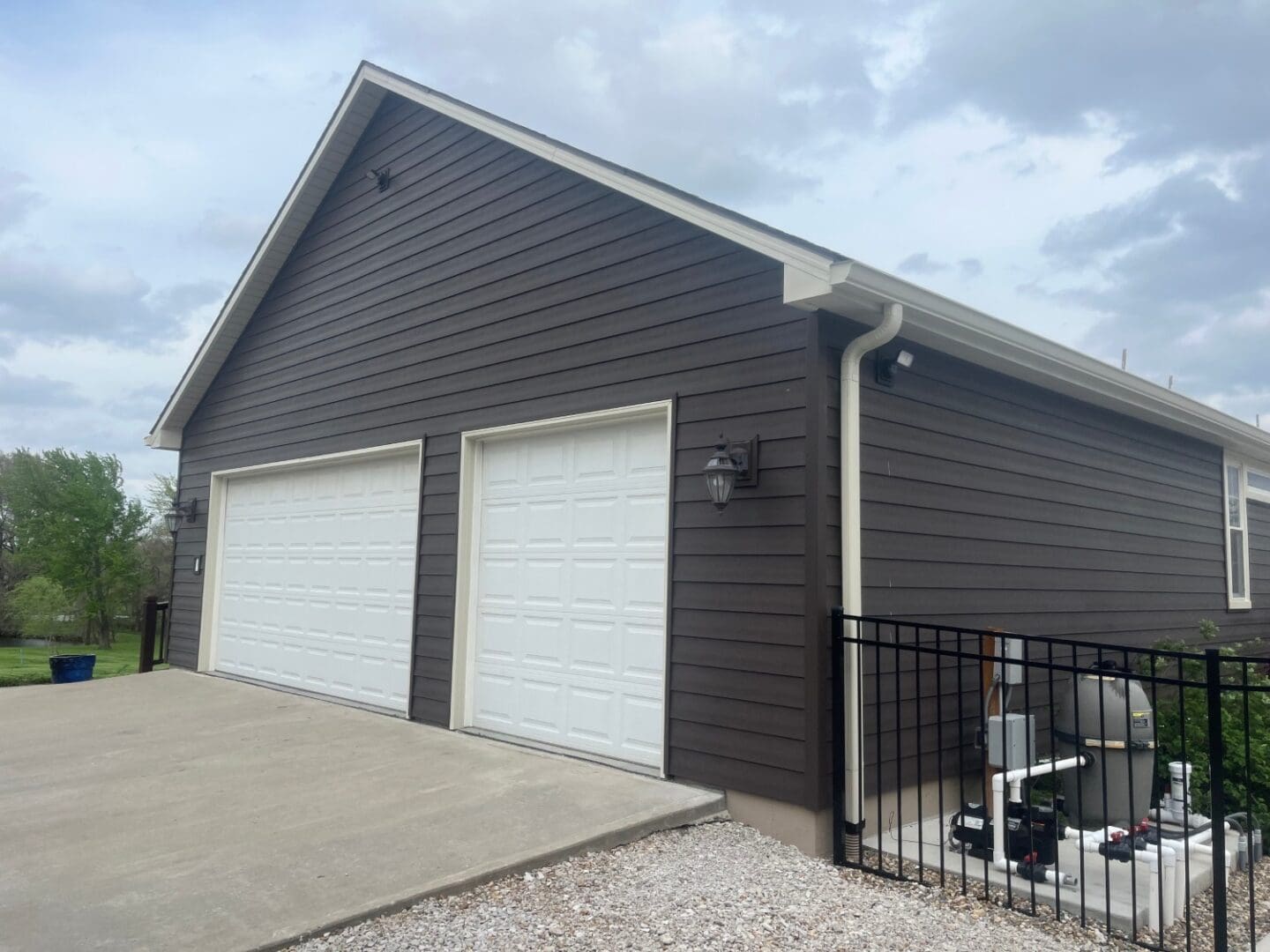 A garage with two doors and a fence around it.