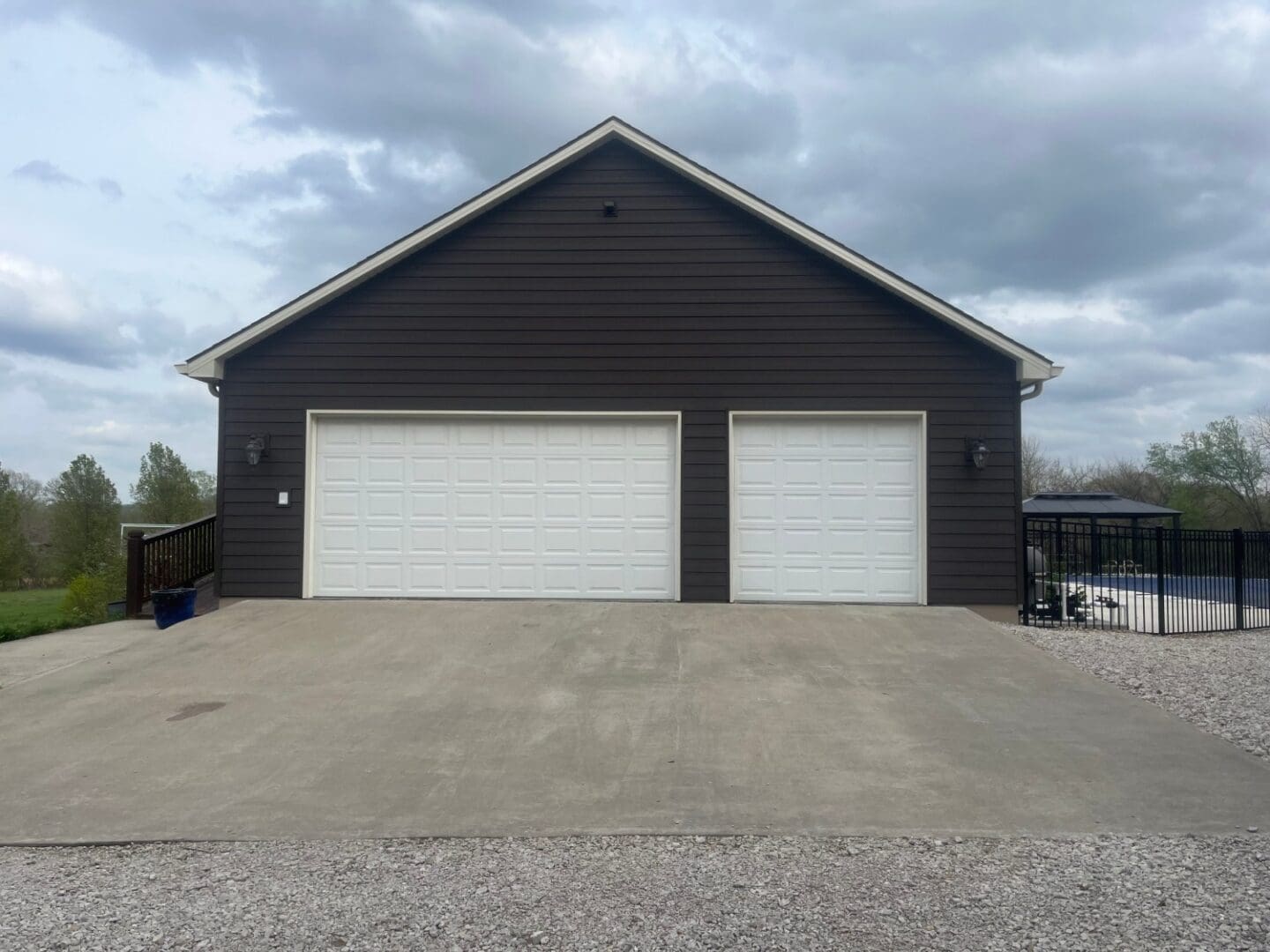 A large garage with two white doors and a black wall.