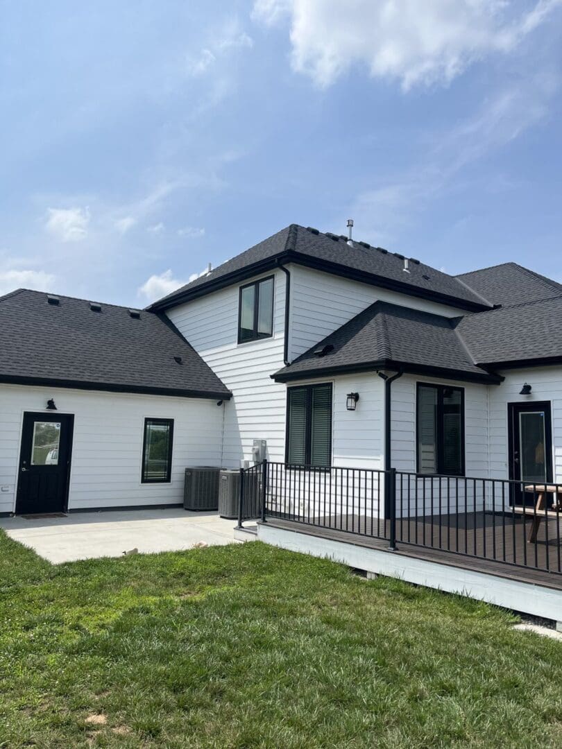 A large white house with black roof and windows.